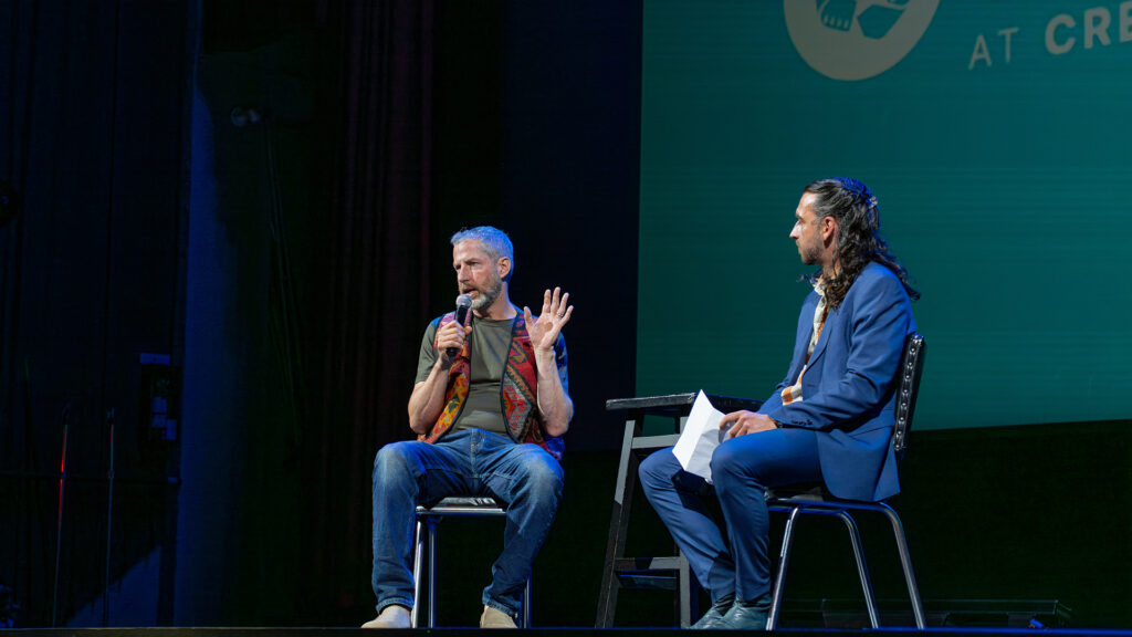 Two people sit on stage.