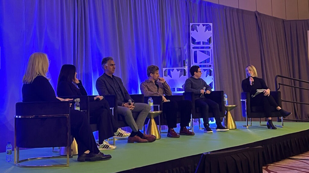 Five panellists sit on stage and the moderator asks questions using a microphone.