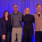 Six people stand together and smile for a photo.